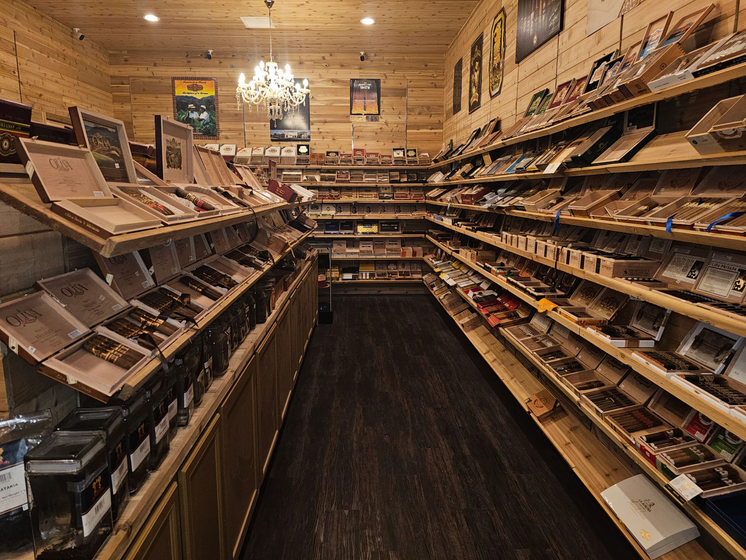 The walk-in humidor aisle, cedar shelves stocked with cigar boxes